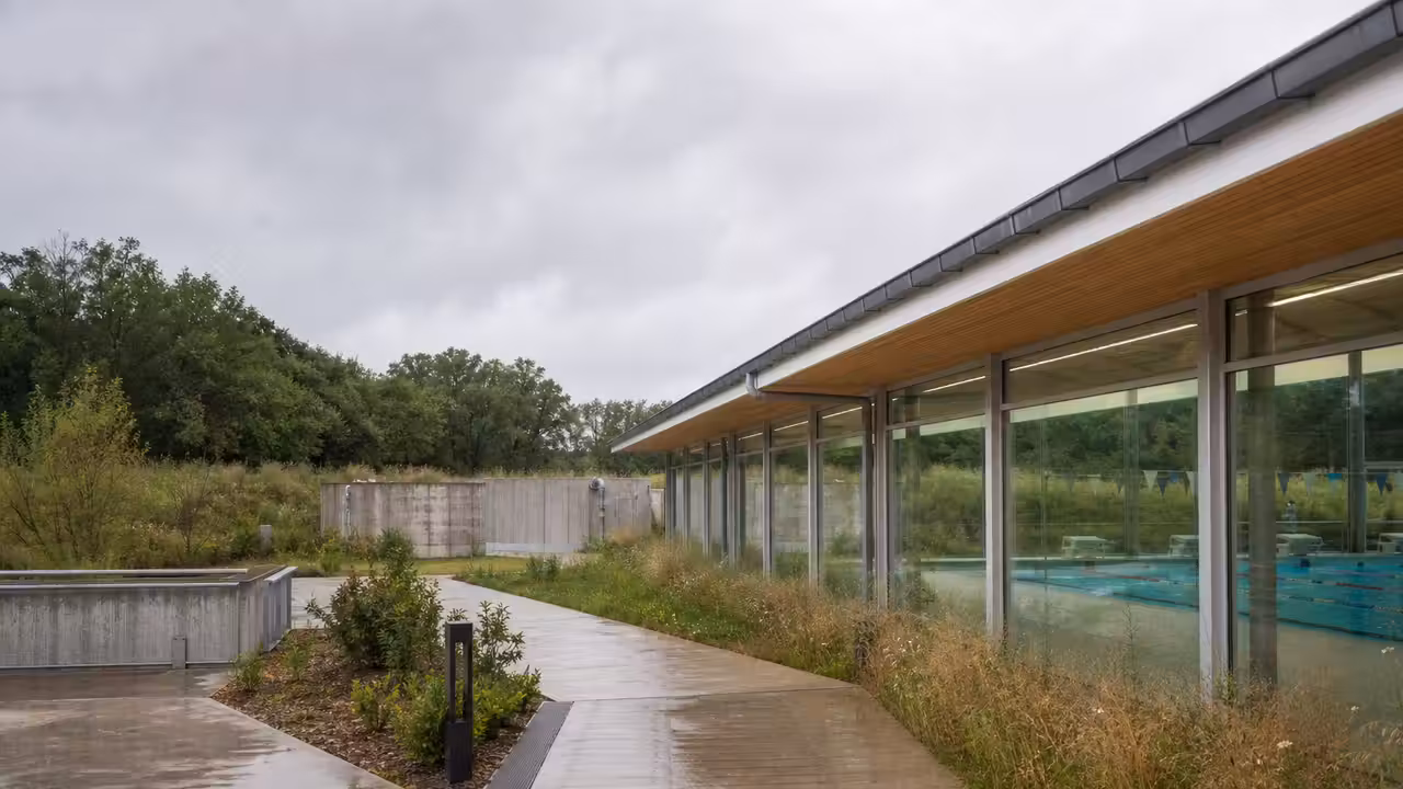 Toiture d’un centre aquatique moderne avec gouttières et cuves de récupération d’eau de pluie