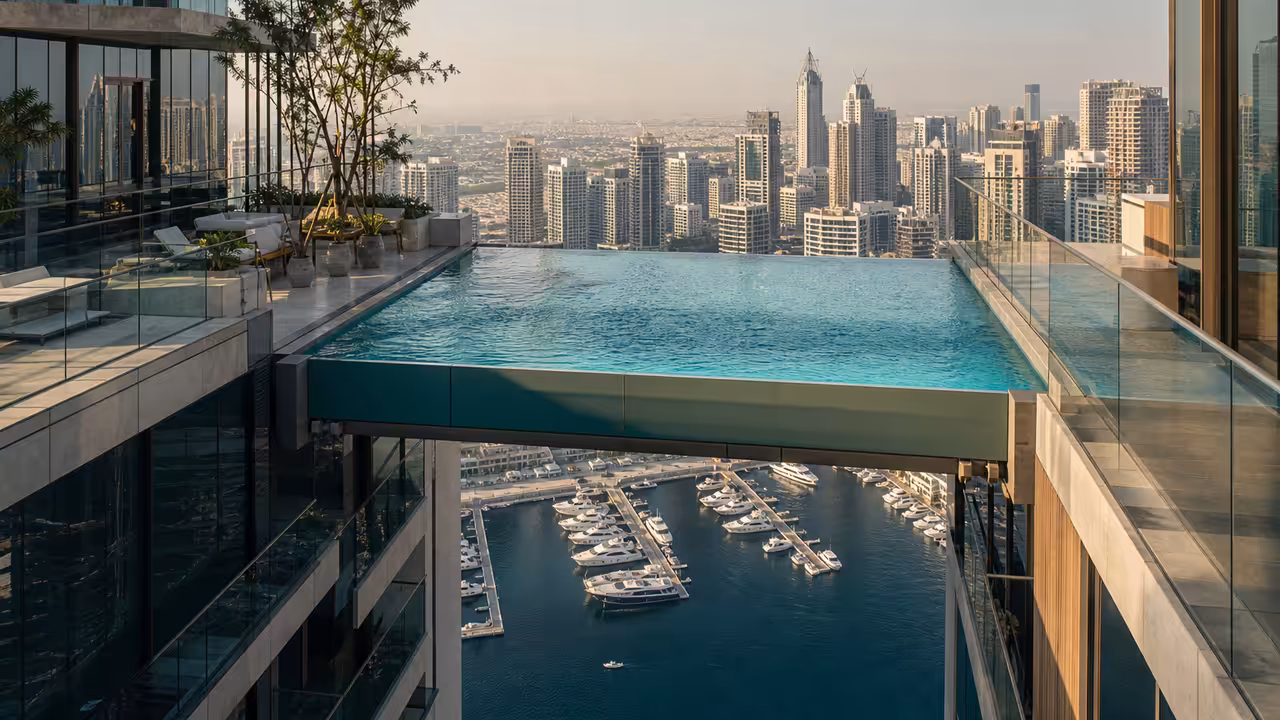 Piscine à débordement suspendue entre deux tours modernes au-dessus d’une marina urbaine à Dubaï