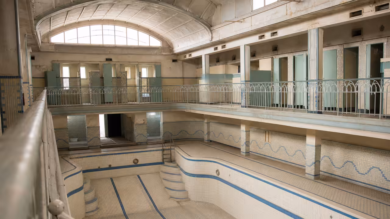 Bassin ancien revêtu de mosaïques bleues dans une piscine municipale française des années 1950