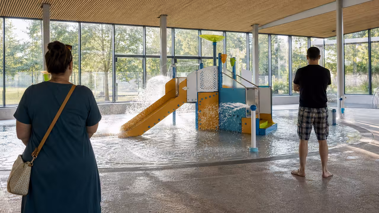 Espace ludique aquatique intérieur avec jets d’eau, petit toboggan et plages antidérapantes pour enfants