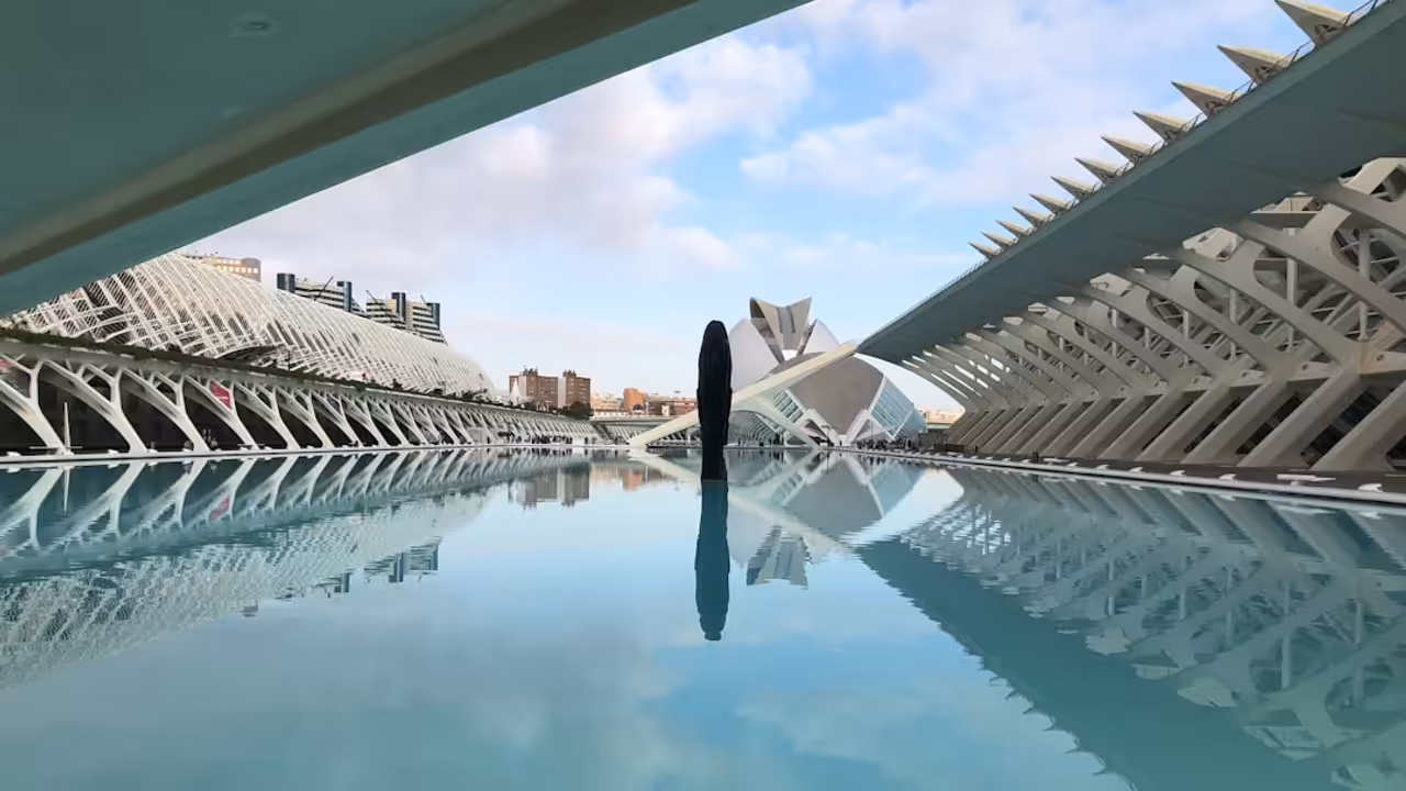 Bassin de natation couvert baigné de lumière naturelle sous le toit ouvrant d’une piscine parisienne