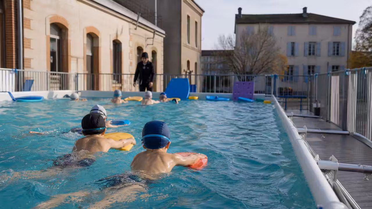 Bassin mobile installé près d’une école, où des enfants s’initient à l’aisance aquatique encadrés