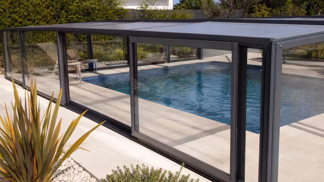 Abri rigide télescopique en aluminium et polycarbonate installé au-dessus d’une piscine enterrée contemporaine