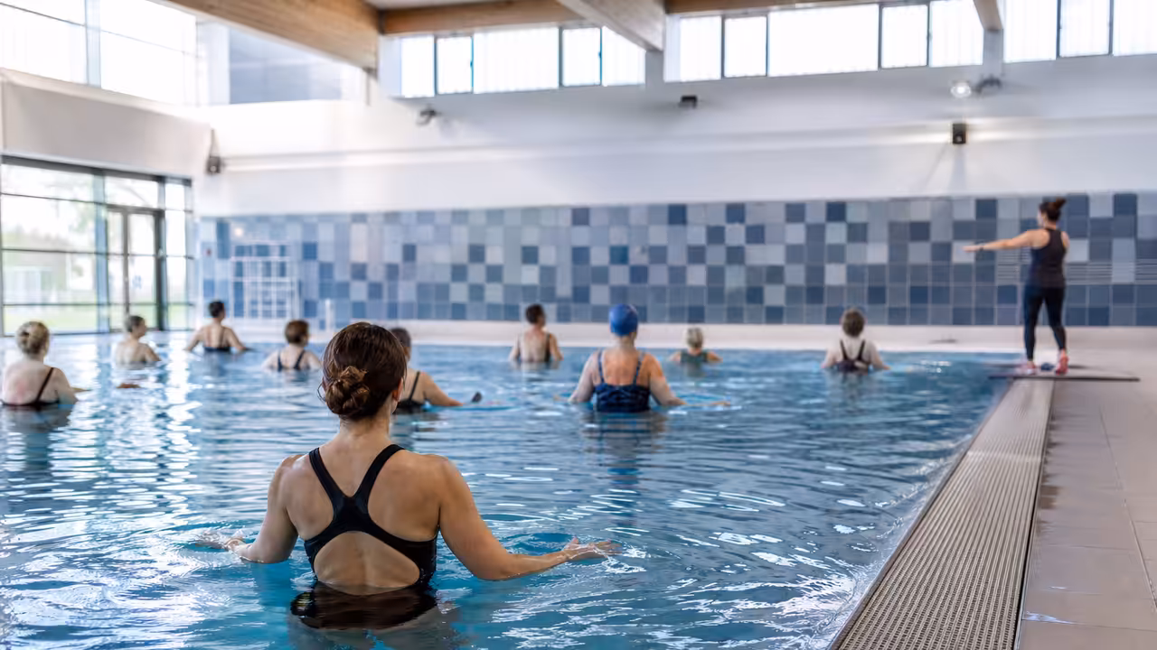 Nageurs adultes et encadrants réunis au bord d’un bassin lors d’une animation aquatique en piscine publique