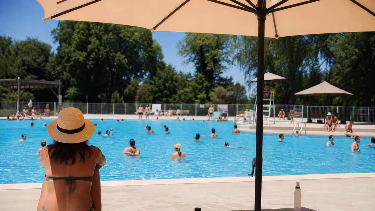 Bassin extérieur d’une piscine municipale fréquenté lors d’une chaude journée d’été, avec zones ombragées