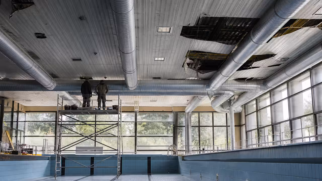 Bassin municipal couvert vide pendant des travaux, avec plafond technique et échafaudage sécurisé