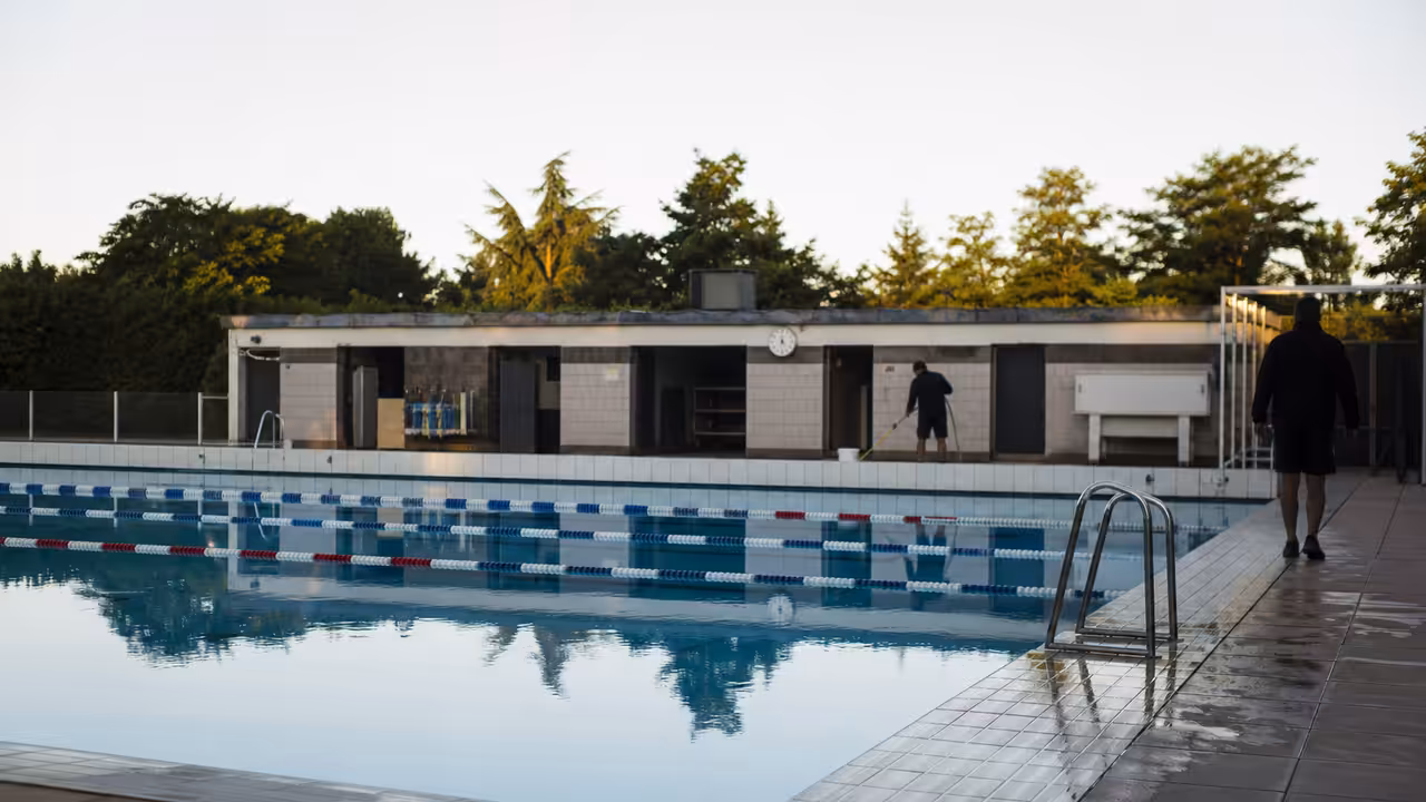 Bassin extérieur d’une piscine municipale avec lignes de nage et accès aux vestiaires par une journée d’été