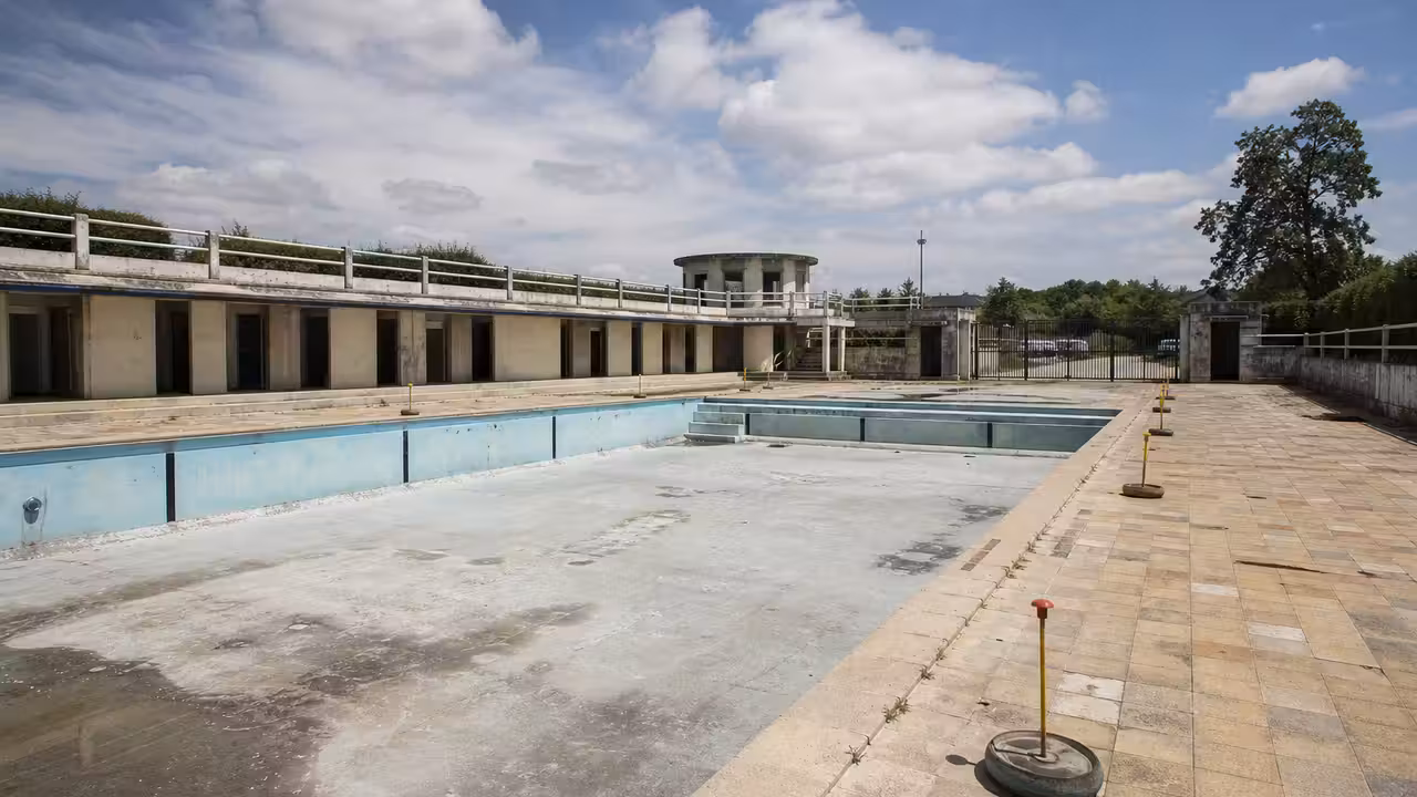 Ancienne piscine extérieure municipale avec bassin vide et bâtiment conservé avant sa réhabilitation