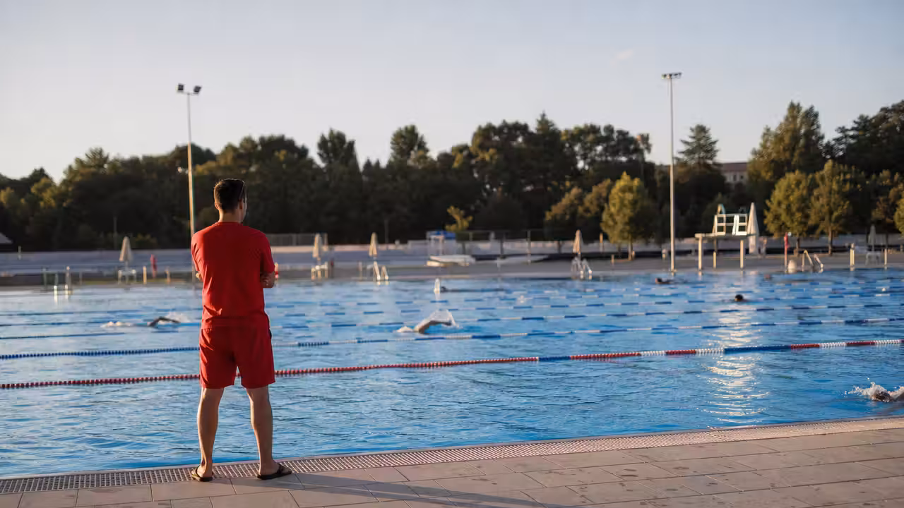Bassin extérieur d’un centre aquatique en fin d’été, avec lignes de nage et personnel en surveillance