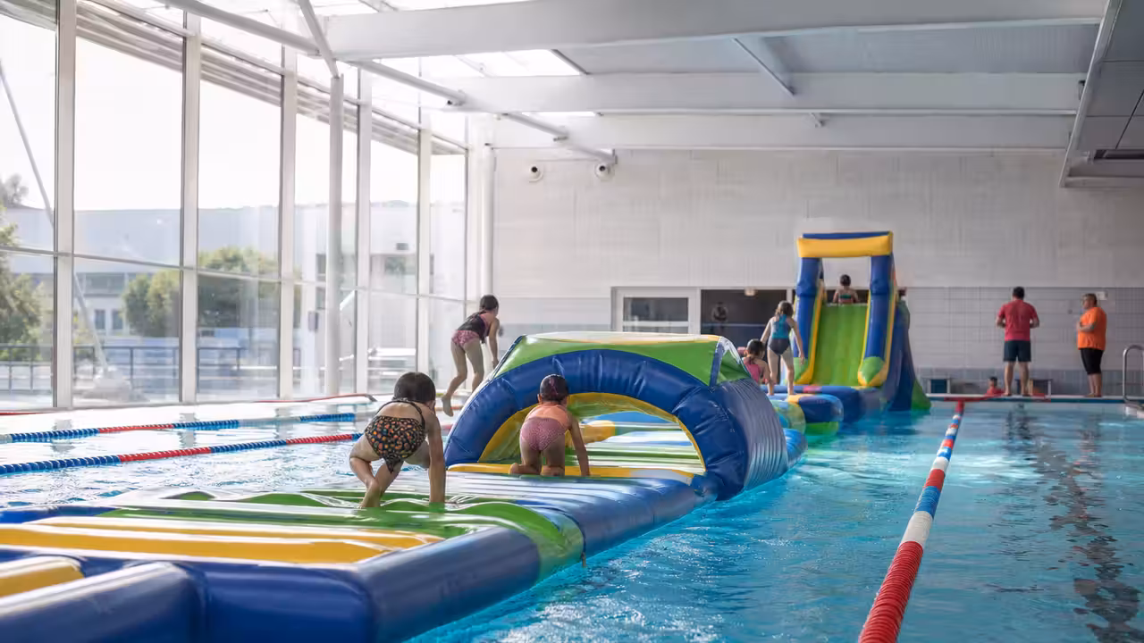 Parcours gonflable installé dans un bassin municipal pendant une animation aquatique familiale encadrée