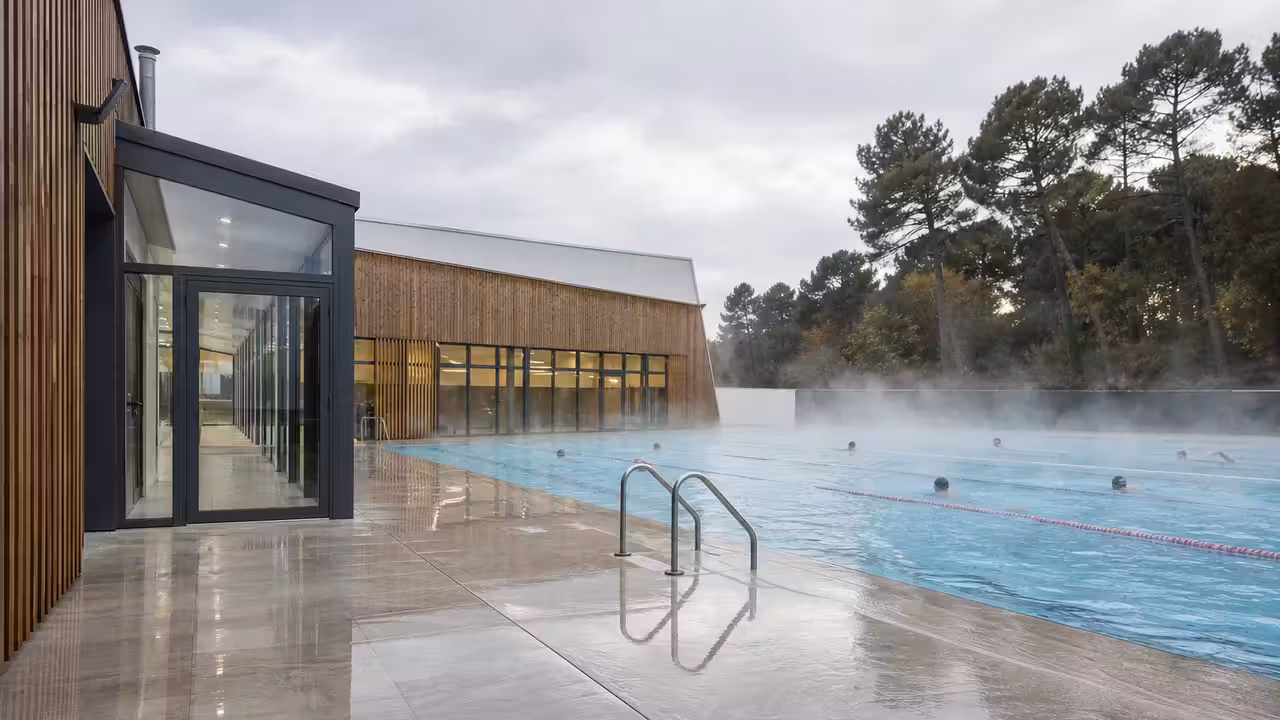 Bassin extérieur chauffé d’une piscine municipale rénovée, avec sas vitré et plages antidérapantes