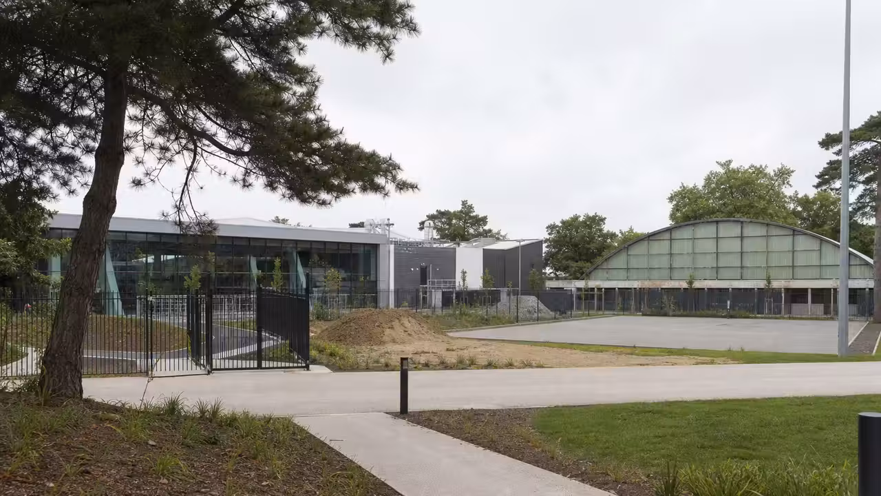 Abords paysagers d’une piscine publique avec halle de tennis et terrains de padel au second plan