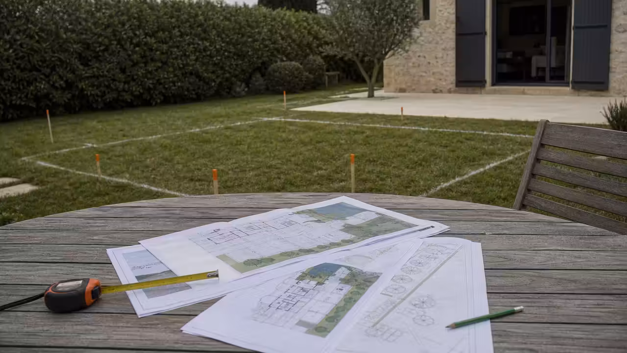 Plan de masse d’une piscine avec mètre, documents d’urbanisme et vue sur un jardin en chantier