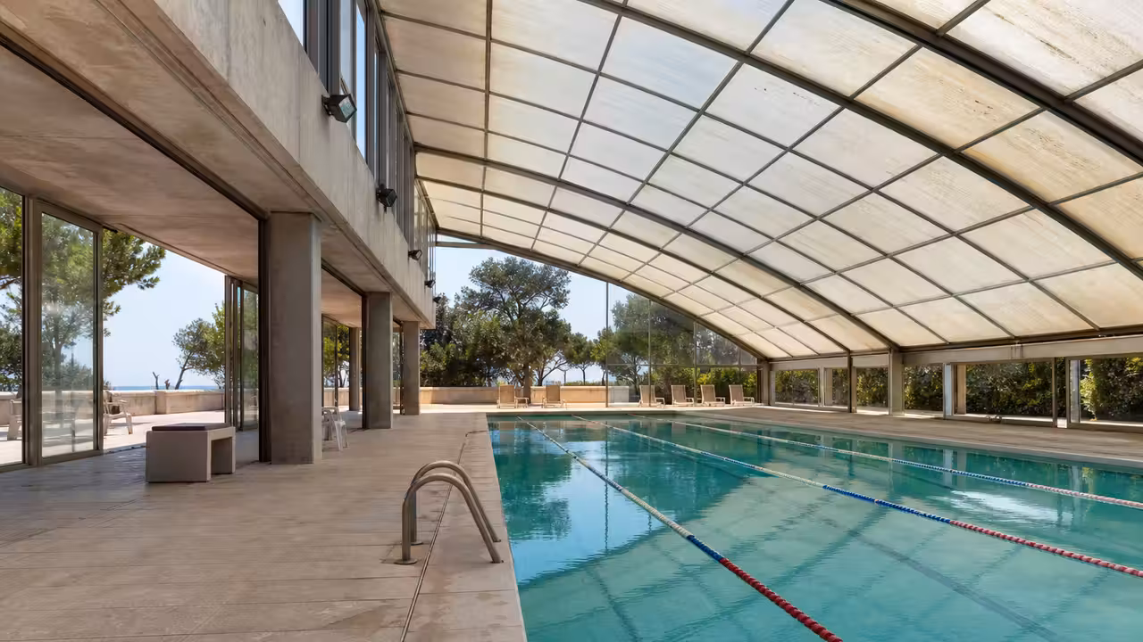 Piscine municipale sous une voûte translucide, avec bassin lumineux et architecture sportive contemporaine