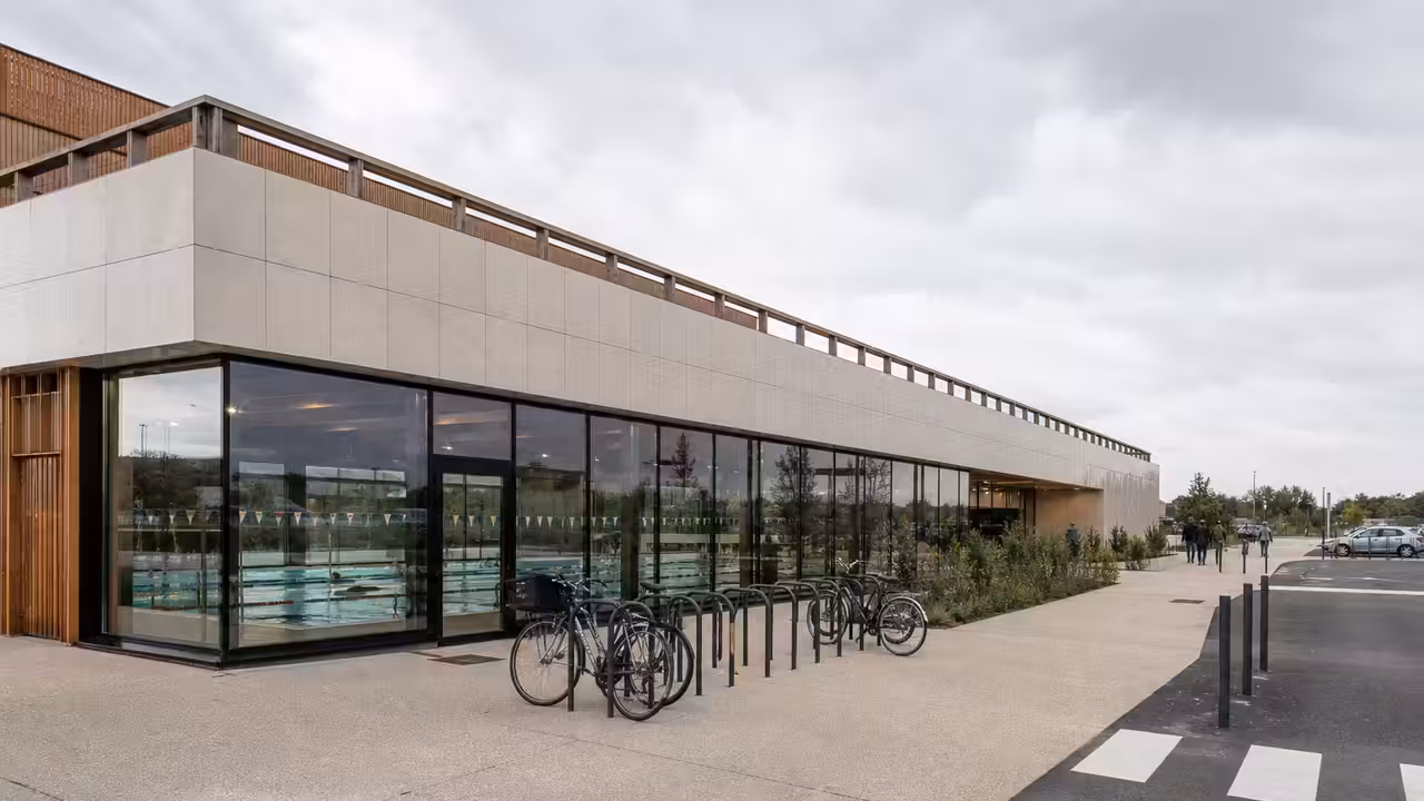 Vue d’illustration d’un centre aquatique public contemporain avec bassin couvert et espace d’accueil lumineux