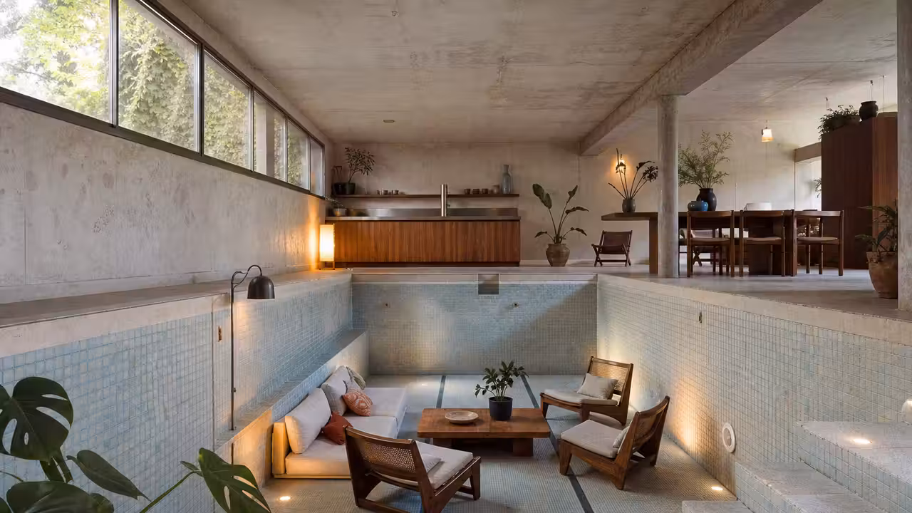 Ancienne piscine intérieure vidée et reconvertie en séjour lumineux avec sol en contrebas et cuisine discrète