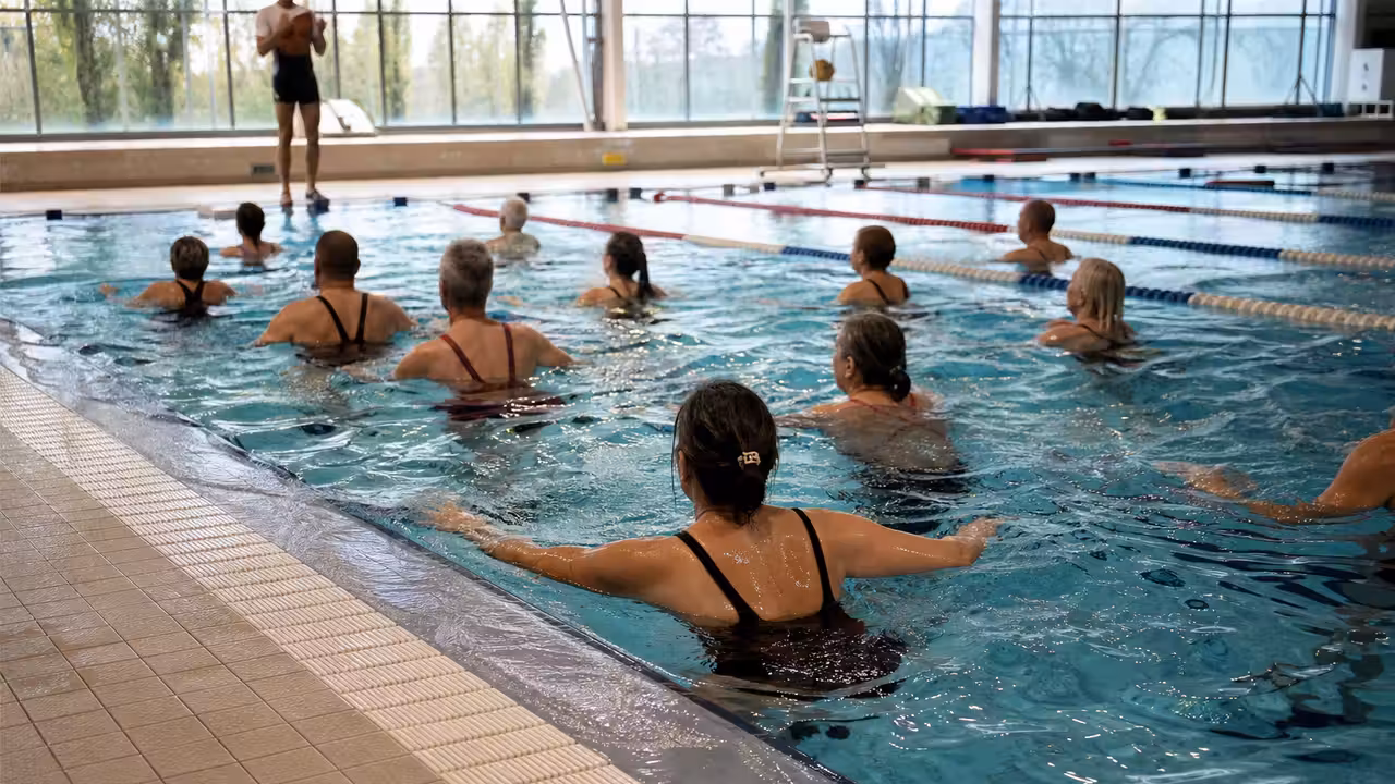 Participants adultes réalisant des exercices de fitness dans un bassin intérieur sous la supervision d’un encadrant