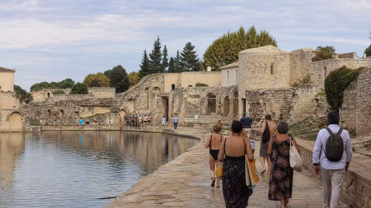 Bord d’un espace de baignade public avec des visiteurs observant des vestiges en pierre lors d’une journée patrimoniale