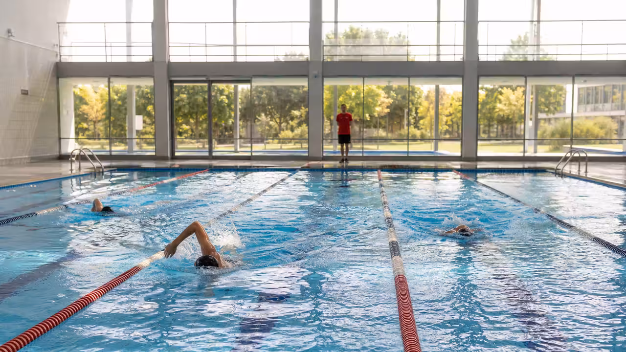 Nageurs adultes dans des lignes d’eau d’une piscine publique bordelaise lumineuse et calme