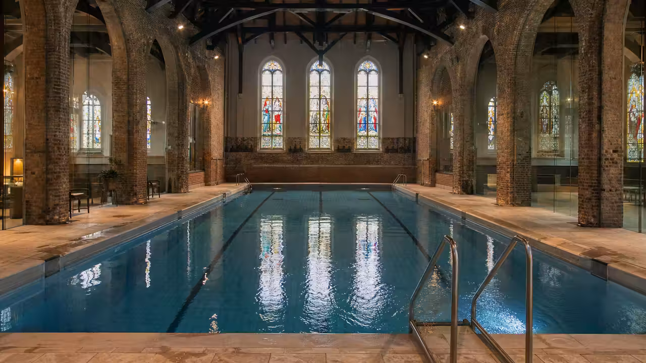 Vue intérieure d’une ancienne église en briques réaménagée en piscine publique lumineuse et contemporaine