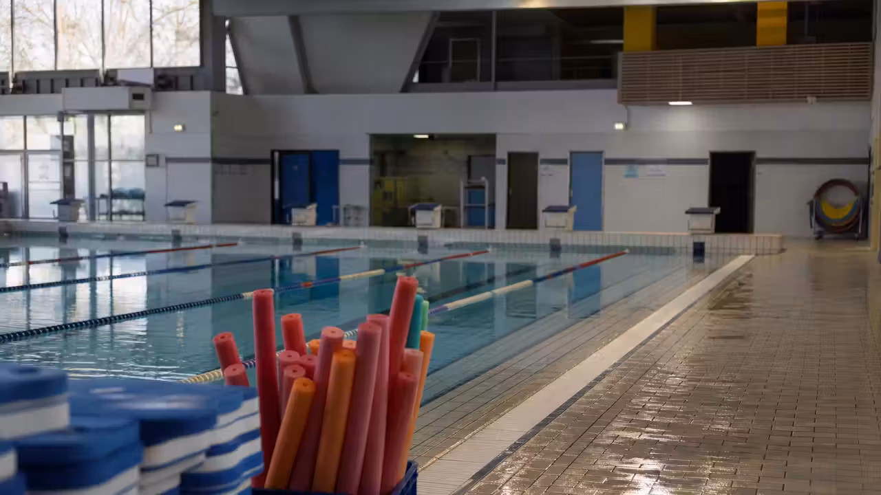 Couloirs d’une piscine municipale vide avec matériel de natation scolaire rangé au bord du bassin