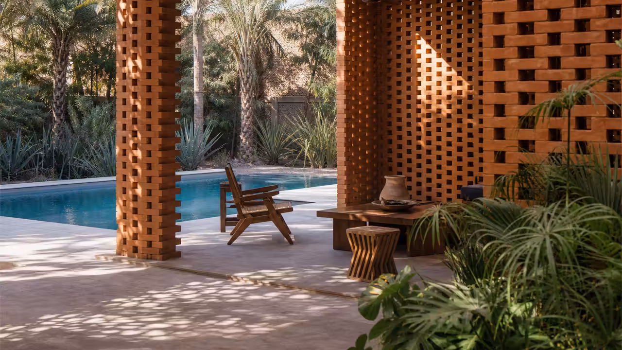 Pavillon de piscine contemporain entouré de claustras ajourés en terre cuite sous une lumière chaude