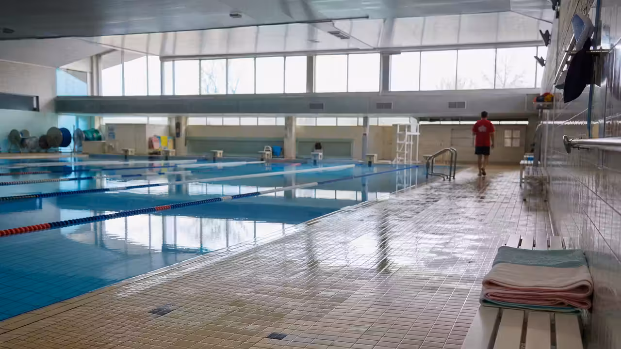 Grand bassin sportif avec lignes d’eau, gradins discrets et lumière naturelle latérale