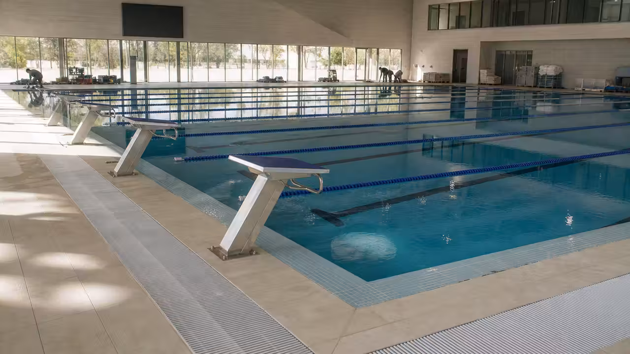 Bassin de natation de 50 mètres rénové, lignes d’eau tendues et plages carrelées sous lumière naturelle