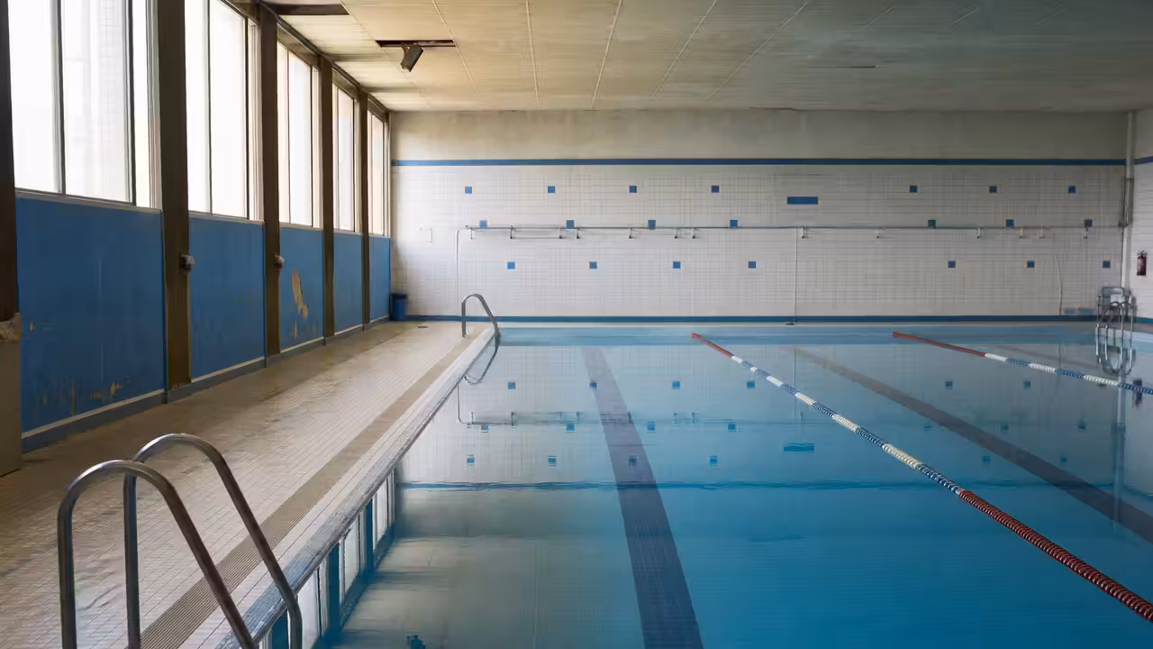 Bassin municipal vide et lignes d’eau calmes avant la fermeture d’un équipement aquatique