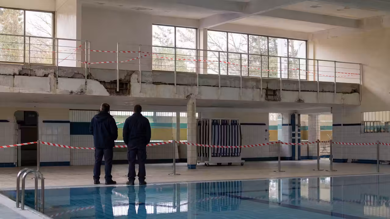 Halle de bassin municipale vide, avec balustrade et paroi en cours d’inspection après un incident