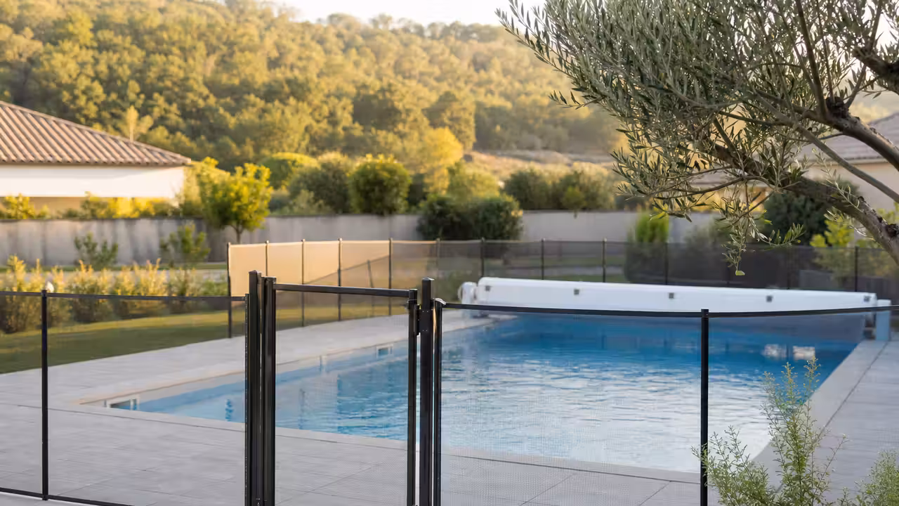 Barrière de sécurité fermée autour d'une piscine familiale, avec portillon verrouillé et margelles dégagées