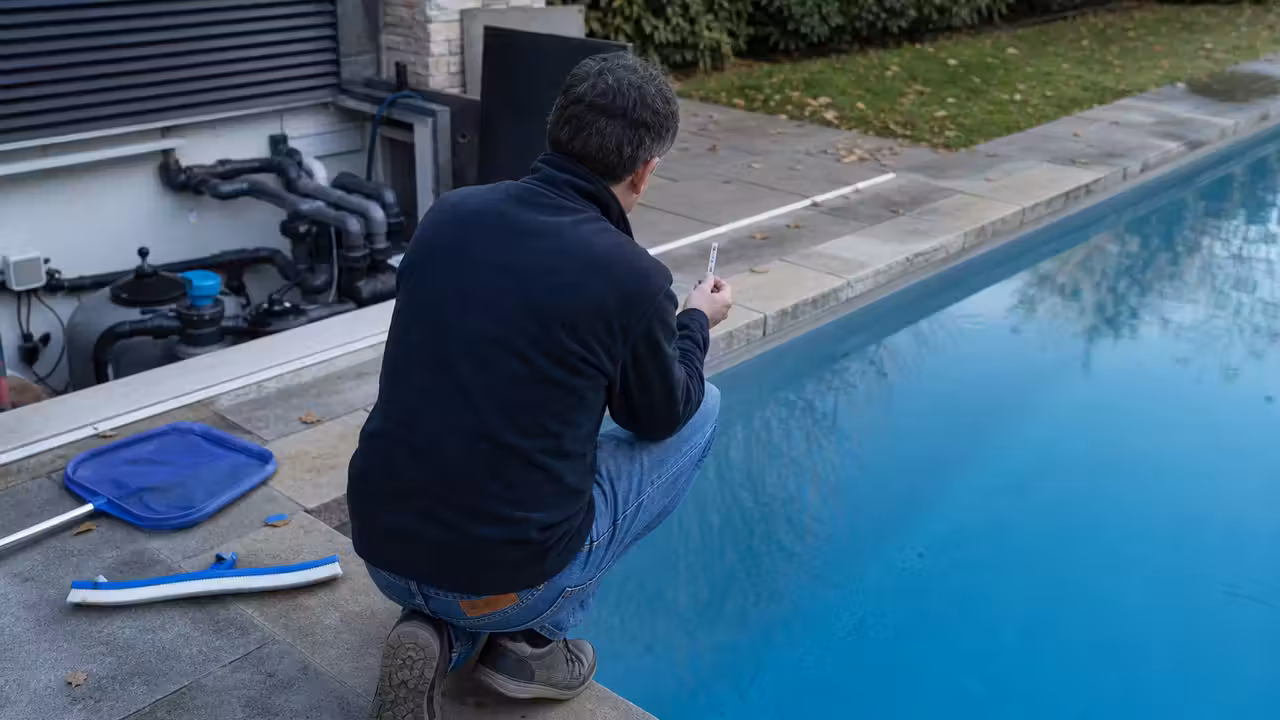 Propriétaire contrôlant l’eau d’une piscine avec une bandelette près du local technique en lumière naturelle