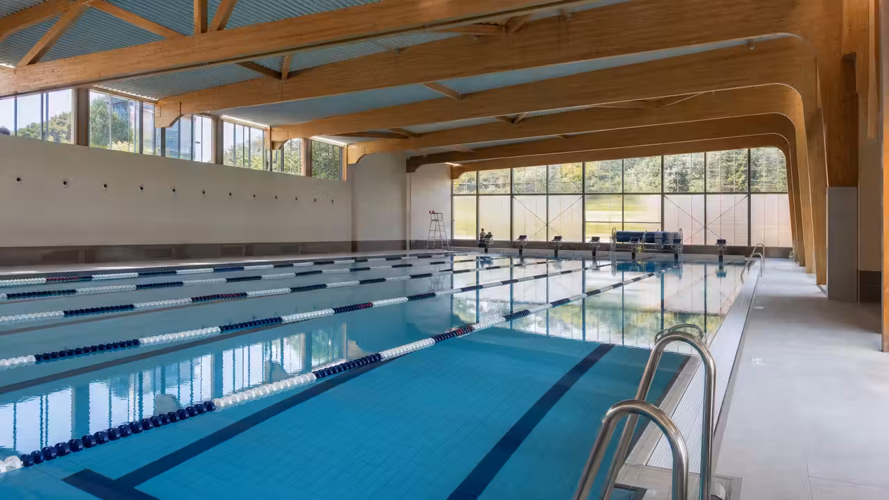 Bassin intérieur rénové d’une piscine publique, lignes d’eau calmes et lumière naturelle sur les carrelages