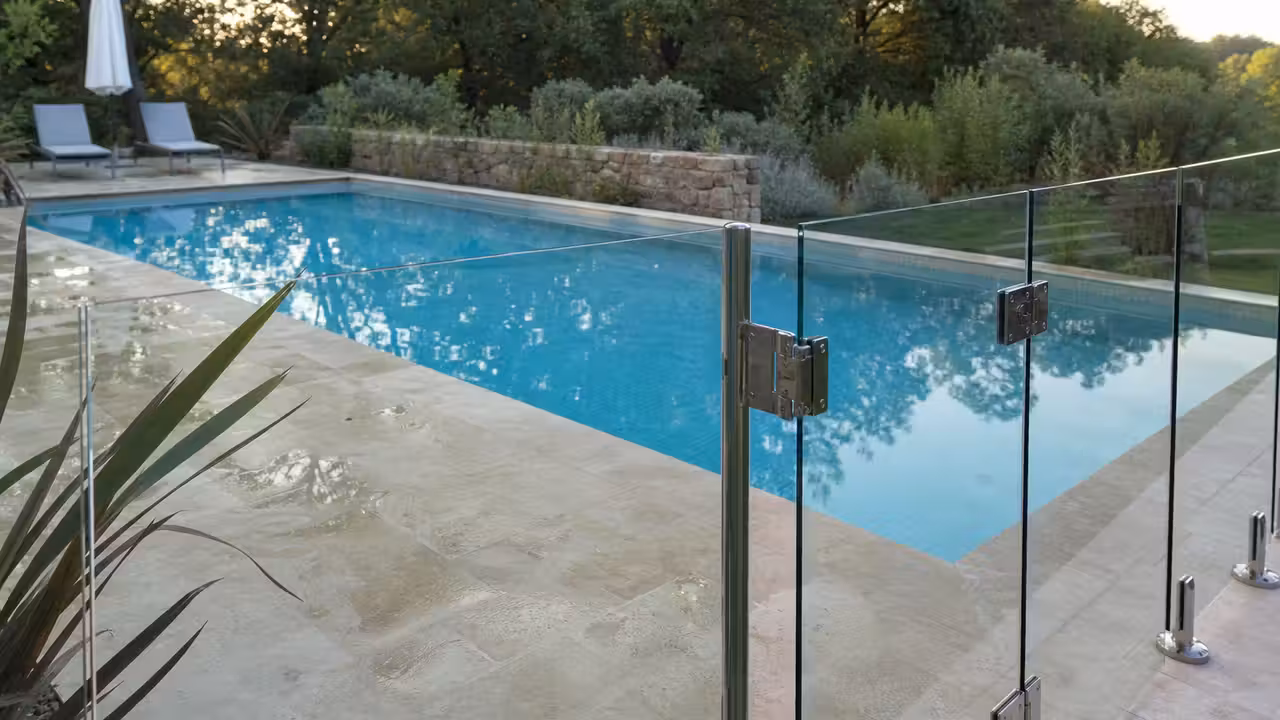Barrière en verre sécurisée entourant une piscine familiale sur une terrasse contemporaine ensoleillée