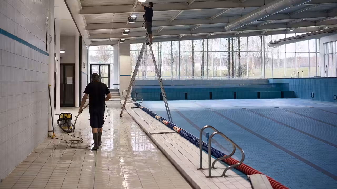 Bassin intérieur vide durant une maintenance technique, avec éclairage de plafond et lignes d’eau retirées