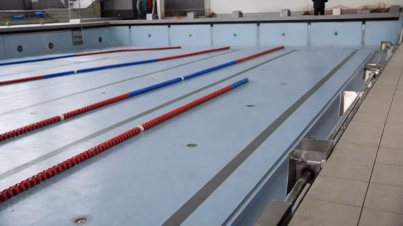 Bassin sportif vide dans une piscine publique, avec lignes d’eau et fond mobile immobilisé