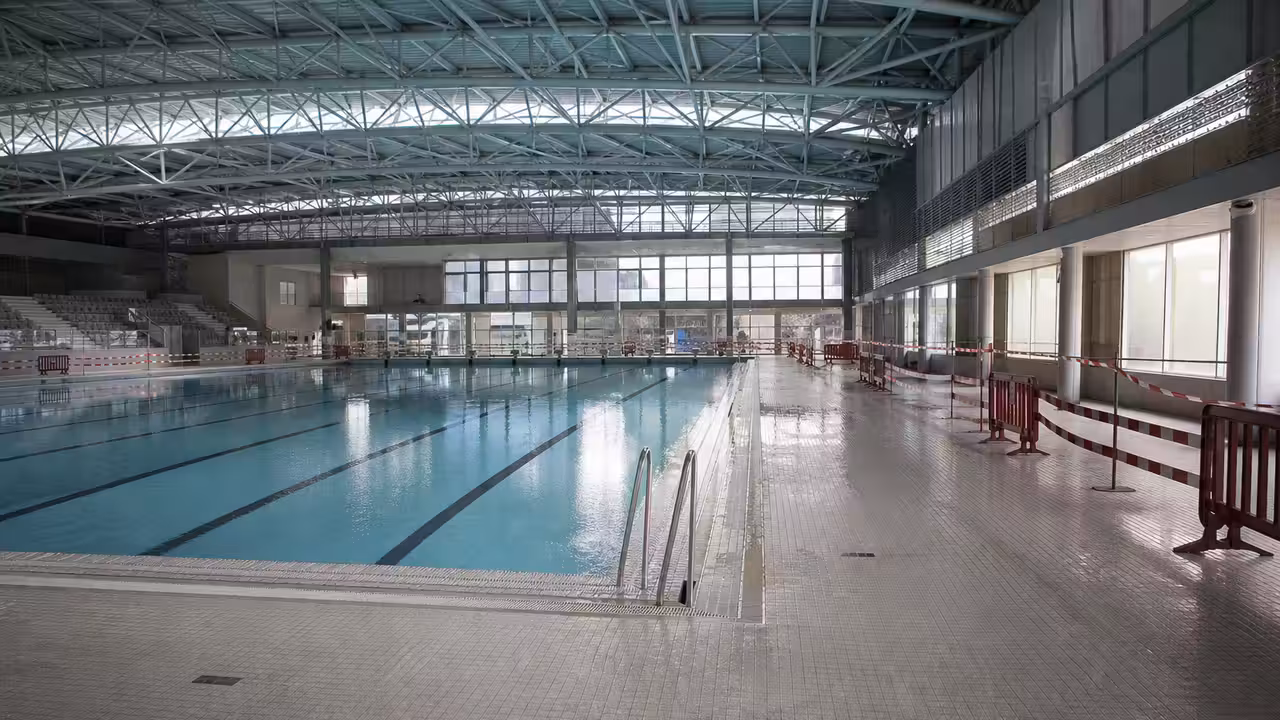 Intérieur d’une piscine publique couverte avec bassin de 25 mètres et structure de toiture visible