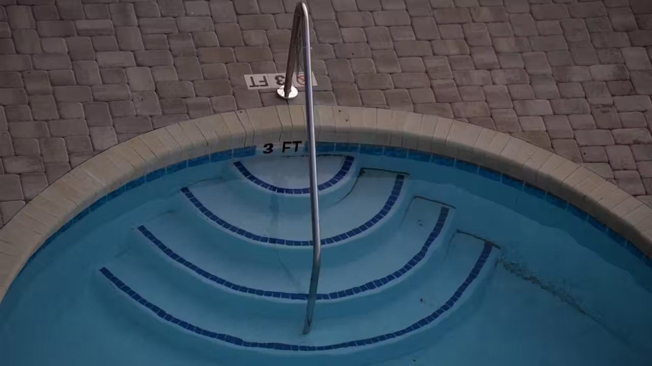 Bassin couvert de piscine publique vide pendant des travaux de rénovation, avec plages carrelées et équipements techniques