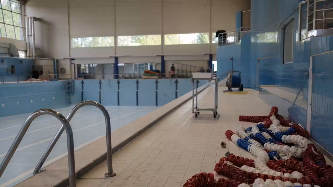 Bassin couvert vide pendant un entretien technique, lignes d’eau retirées et matériel au bord de l’eau