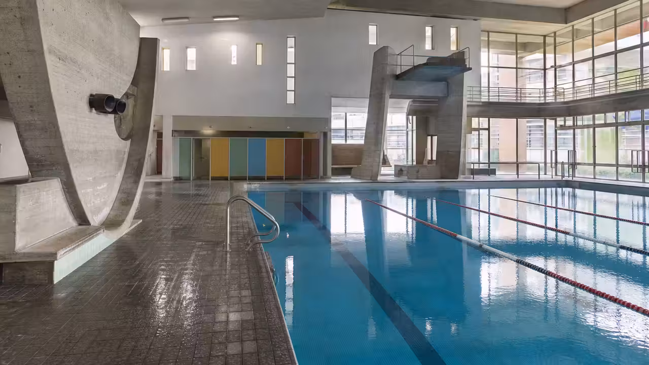 Vue intérieure de la piscine André Wogenscky à Firminy, avec bassin couvert et architecture moderniste rénovée