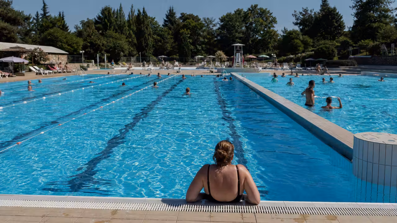 Bassin extérieur de piscine municipale animé avec nageurs, lignes d’eau et espace de détente ombragé