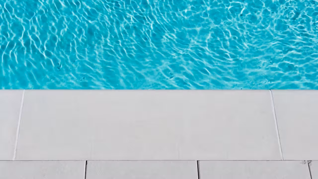Bassin extérieur d’une piscine municipale avec baigneurs, maîtres-nageurs et espaces ombragés en été