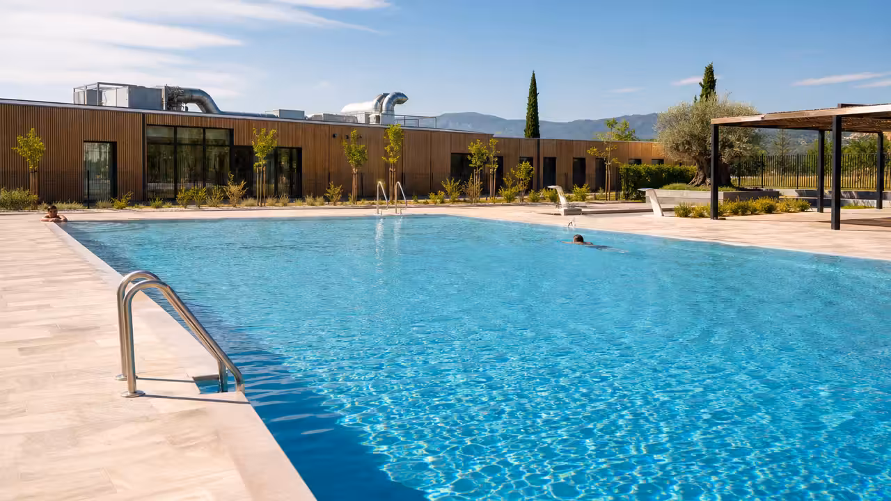 Piscine municipale rénovée avec bassins, plages claires, espaces végétalisés et équipements techniques modernisés