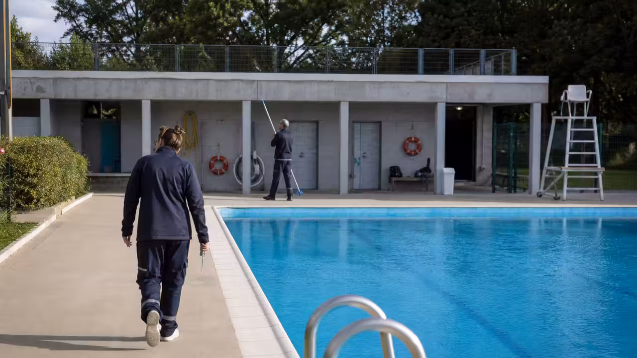 Agent de piscine municipale préparant l’accueil et la surveillance d’un bassin extérieur avant l’ouverture