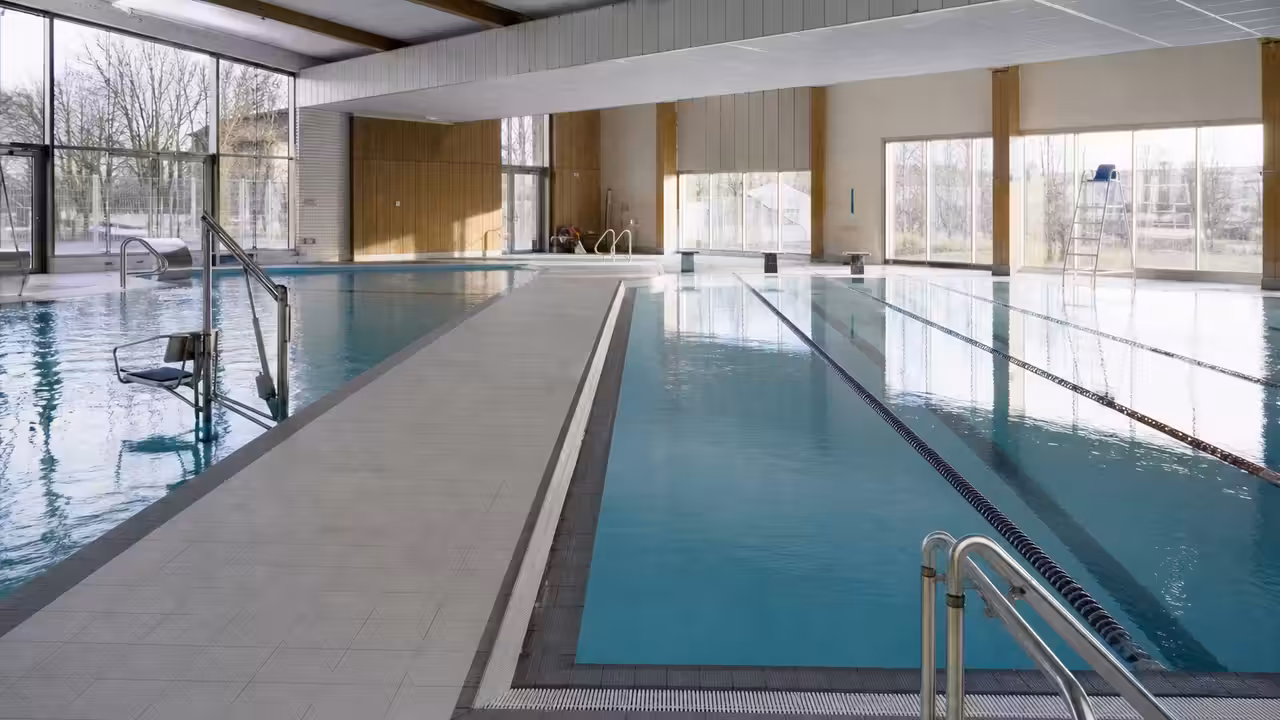 Vue intérieure de bassins d’une piscine publique moderne avec lignes d’eau et baies vitrées lumineuses