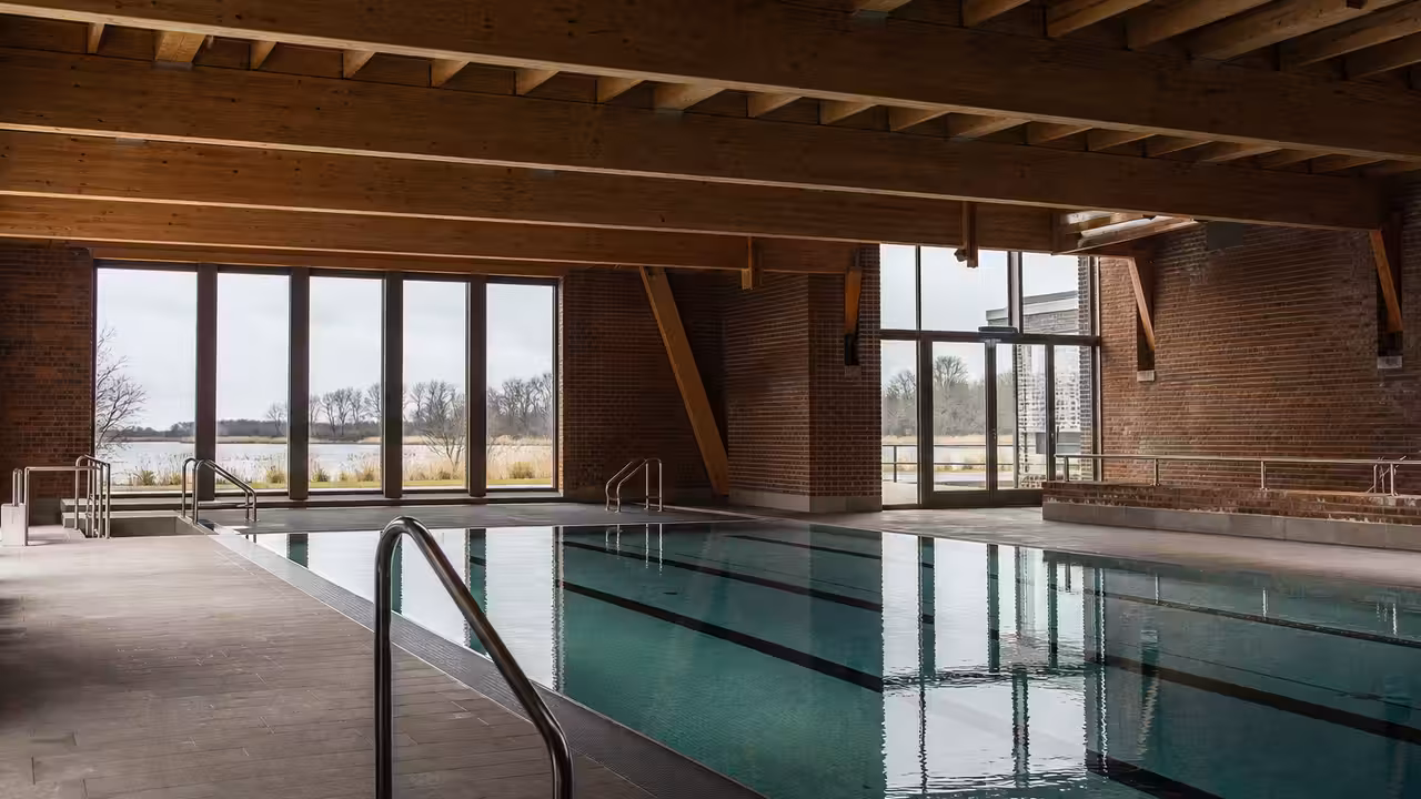 Intérieur d’un centre aquatique contemporain avec charpente en bois, brique apparente et lumière naturelle
