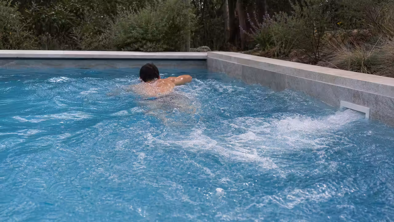 Nageur de dos dans une piscine privée équipée d’un courant de nage large et régulier