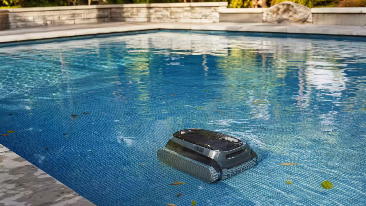 Robot de piscine sans fil nettoyant le fond d’un bassin contemporain aux parois en mosaïque bleue.