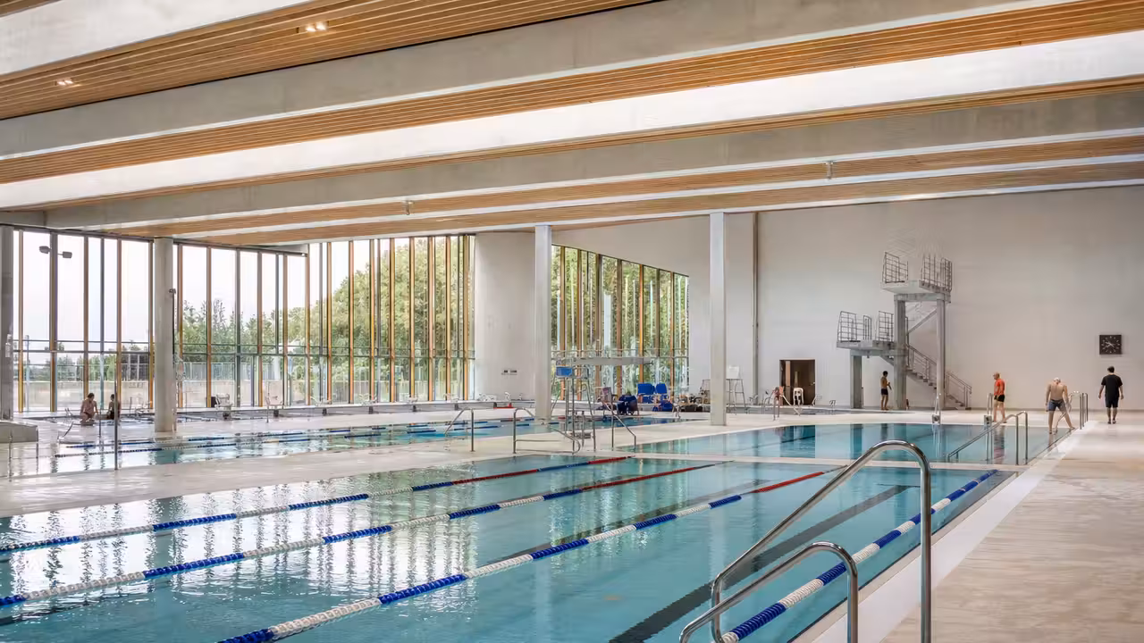 Vue intérieure lumineuse d’une piscine publique moderne avec plusieurs bassins et lignes de nage inoccupées