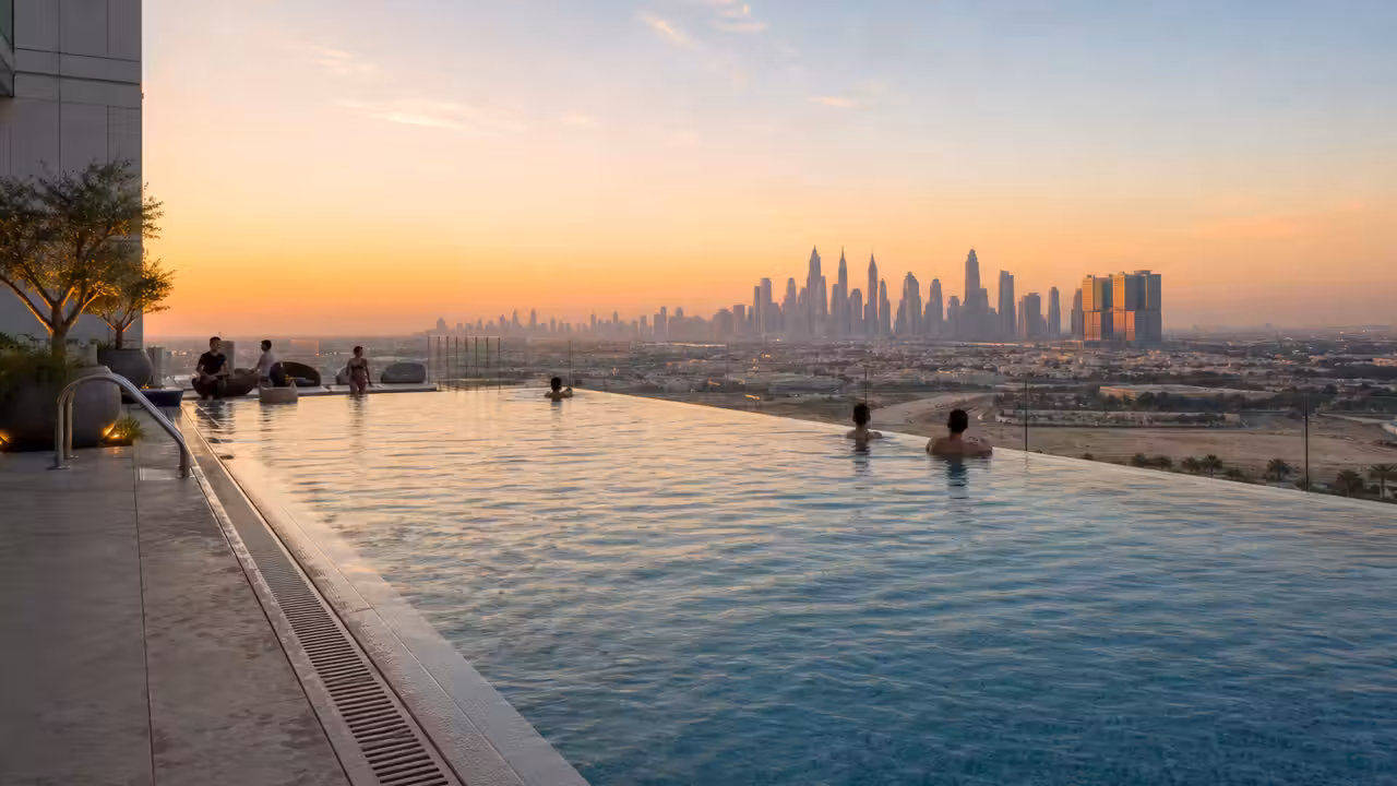 Piscine à débordement sur un toit-terrasse, face à la skyline urbaine au coucher du soleil